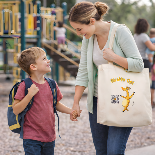 Woman holding a child's hand with a canvas tote bag featuring Gertie the Brave Giraffe character and QR code at a playground.